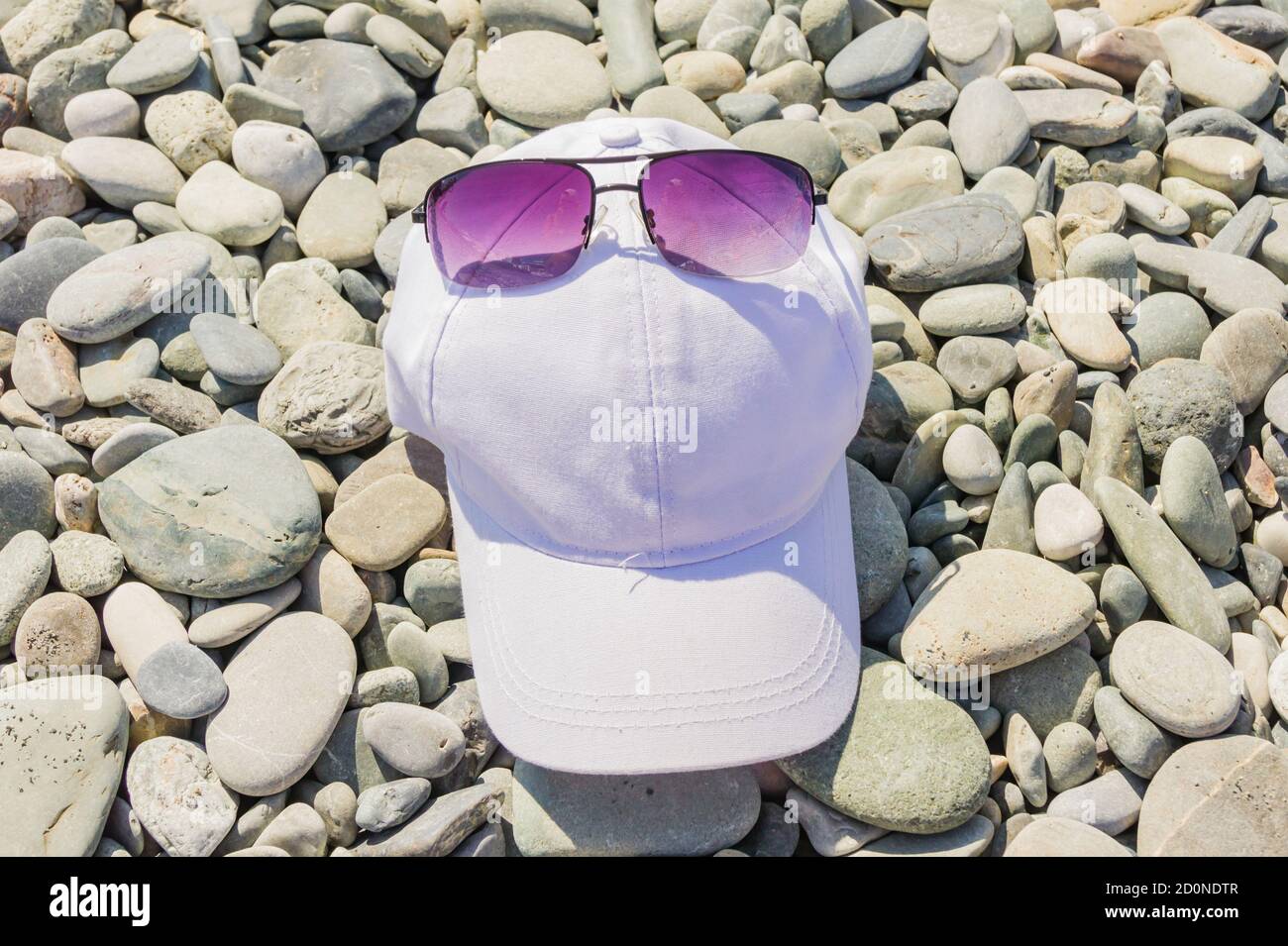 Baseball caps and sunglasses lie on a gravel Stock Photo Alamy