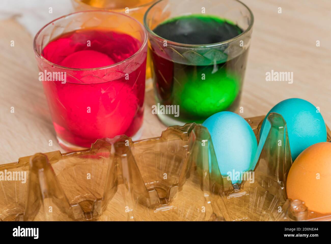 Glass with orange, red and green paint for Easter eggs. Easter Egg decorating. Stock Photo