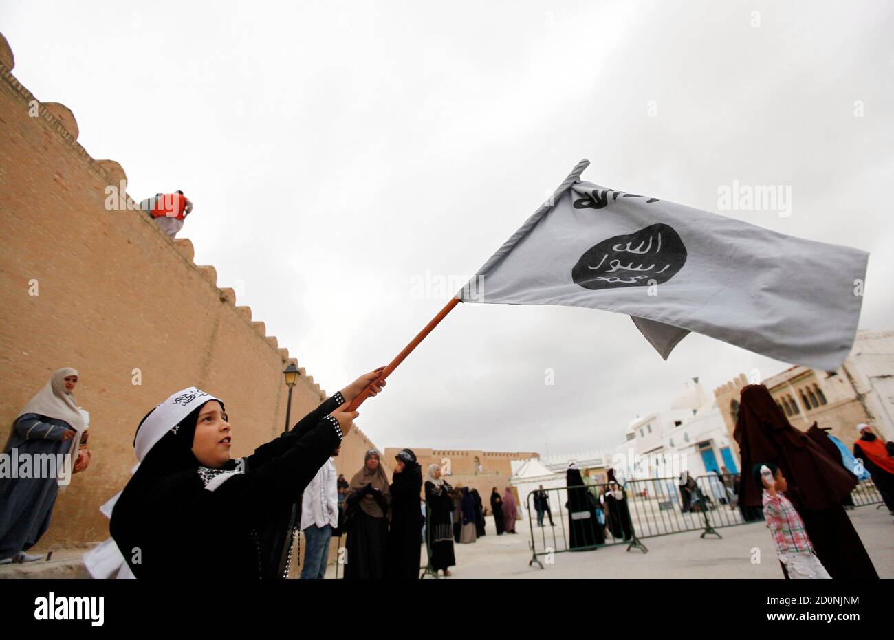 A young Tunisian girl dressed in black robes waves a white flag inscribed with Islamic verses at a rally of Salafi Islamists in the central town of Kairouan on May 20, 2012. Waving black flags embossed with Islamic verses, thousands of radical Islamists rallied in the central Tunisian town of Kairouan on Sunday to demand a wider role for religion in a country long considered one of the Arab world's most secular. REUTERS/Anis Mili (TUNISIA - Tags: RELIGION) ) Stock Photo
