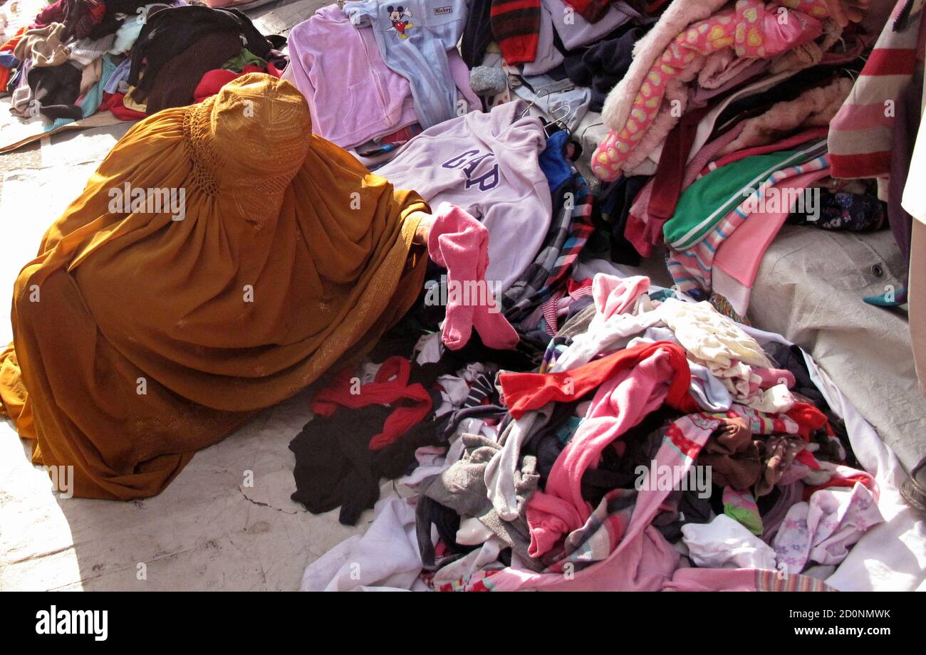 A woman sorts used winter clothes for sale in a temporary stall at a market in Mingora, Swat valley November 23, 2012. REUTERS/Hazrat Ali Bacha (PAKISTAN - Tags: BUSINESS SOCIETY) Stock Photo