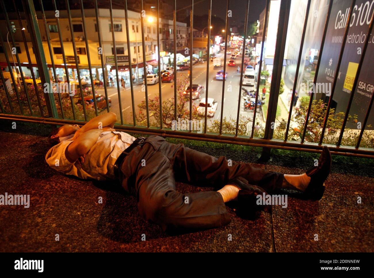 A man is pictured unconscious on an overhead pedestrian bridge overlooking Geylang district in Singapore February 8, 2013. Singapore has long cultivated a reputation as a clean, safe and regimented place to live and do business in a turbulent region, but the apparently major role of Singaporeans in a global soccer match-fixing scandal shows a seamy underside often out of view. REUTERS/Edgar Su (SINGAPORE - Tags: CRIME LAW SOCIETY) Stock Photo