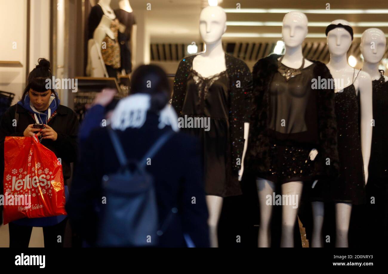A woman checks her mobile phone as she leaves a Lefties shop in central  Madrid December 10, 2013. Spanish retailer Inditex, owner of Zara and  Lefties, said on Wednesday sales rose 10