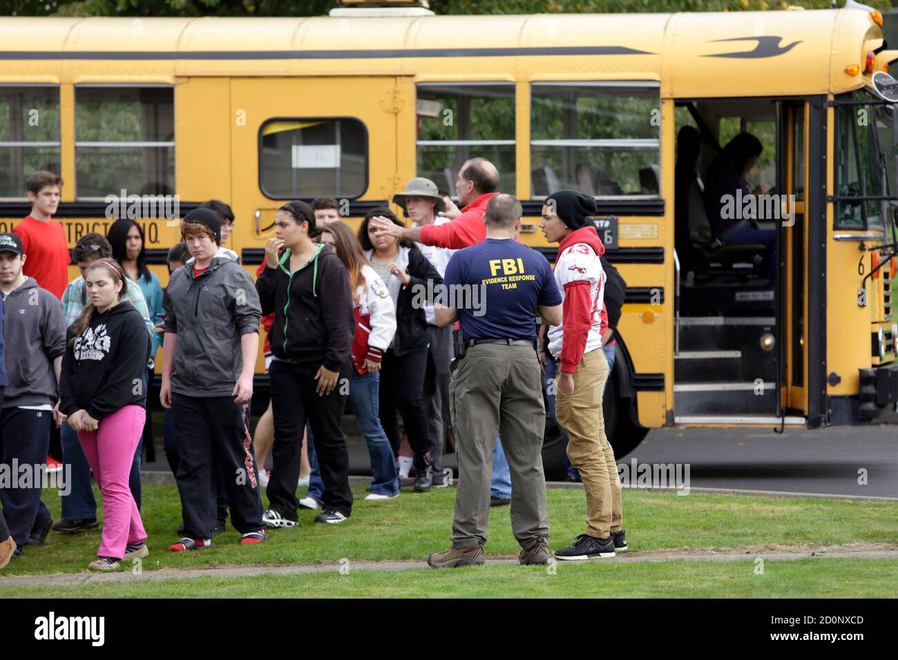 Students exit a bus with an FBI agent (R) speaking to students as they arrive at Shoultes Gospel Hall church after a student opened fire at Marysville-Pilchuck High School in Marysville, Washington October 24, 2014. The student opened fire in the cafeteria of Marysville-Pilchuck High School on Friday, killing a classmate and wounding at least four others before taking his own life amid the chaos of students scrambling to safety, authorities said.   REUTERS/Jason Redmond   (UNITED STATES - Tags: CRIME LAW EDUCATION) Stock Photo