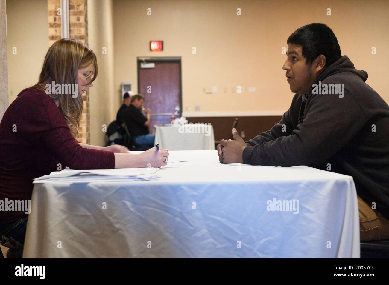 Bazileo Hernandez (R) talks to a recruiter at a hiring event hosted at a local hotel by the oilfield services company RockWater Energy Solutions in Williston, North Dakota January 22, 2015. After a week in Williston, Hernandez and his friends were still looking for steady work. Like so many before them, Terra Green, Jeff Williamson and Bazileo Hernandez came to North Dakota's oil country seeking a better life. They just came too late. Itinerant, unskilled workers could as recently as last spring show up in the No. 2 U.S. oil producing state and vie for salaries north of $100,000 per year with  Stock Photo