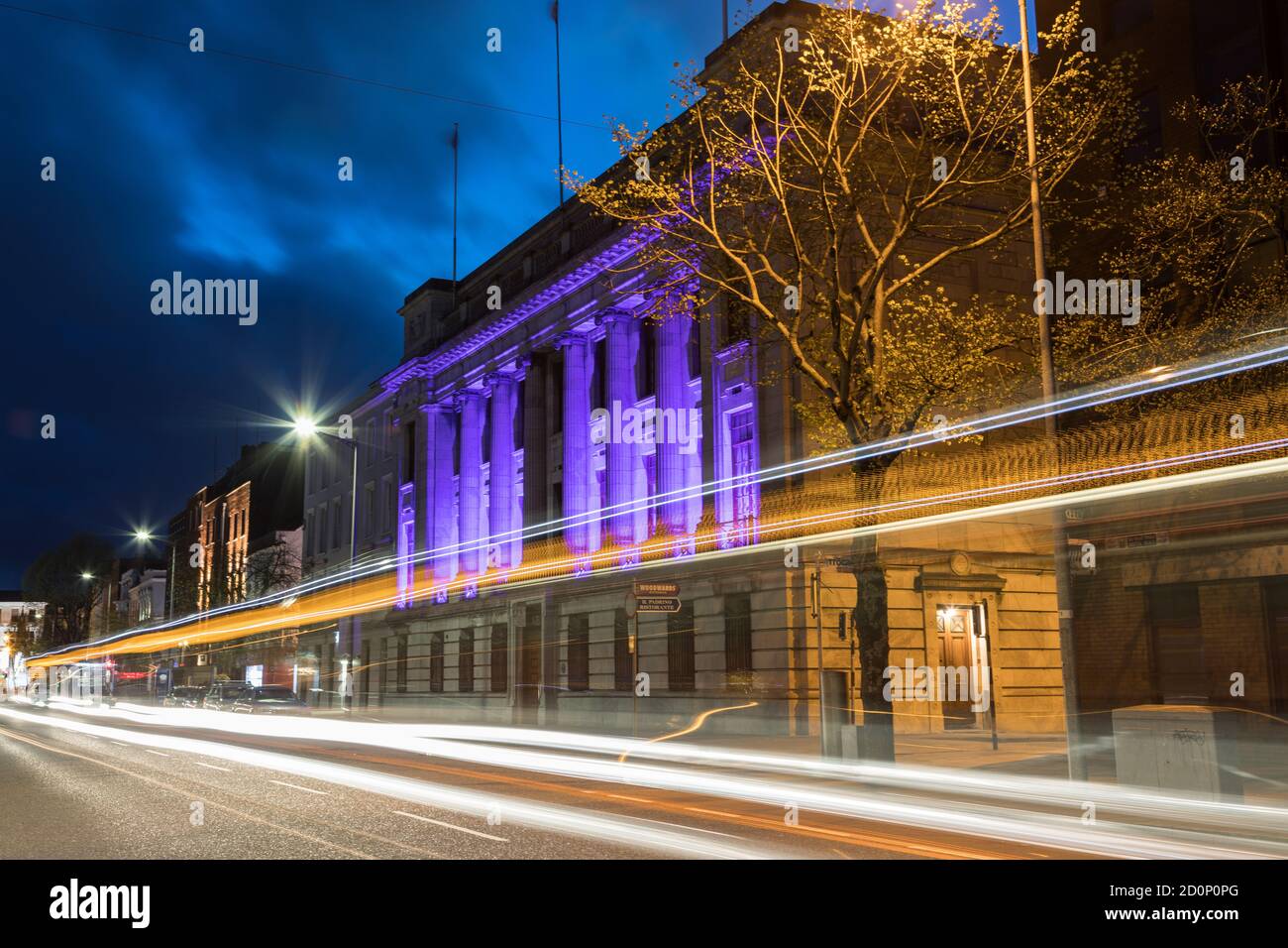 Cork City, Ireland - 22nd April, 2018: Light streaks from cars and a bus zooming past the Allied Irish bank building on South Mall street in Cork city Stock Photo