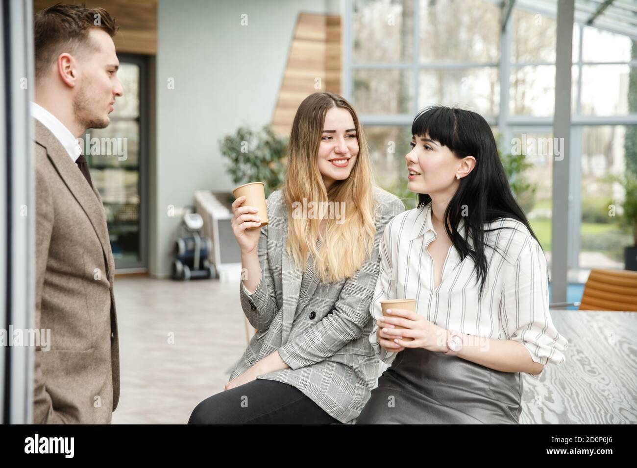 https://c8.alamy.com/comp/2D0P6J6/two-girls-are-talking-with-a-guy-they-are-sitting-in-an-office-building-2D0P6J6.jpg