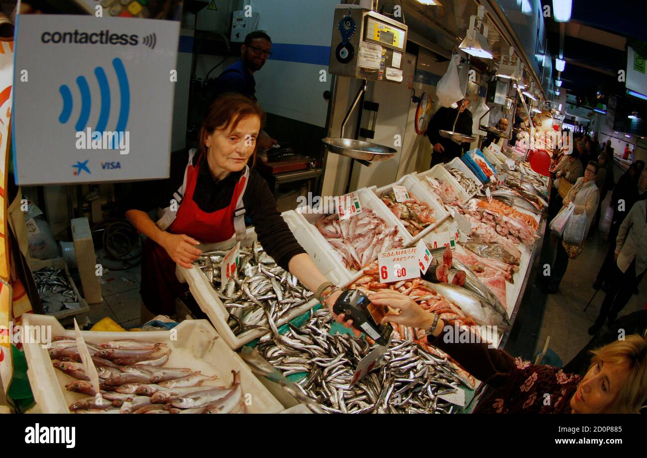 A woman uses a contactless credit card system for a payment in a local fish  market in Palma de Mallorca on the Spanish Balearic island in Mallorca  December 18, 2012. The system