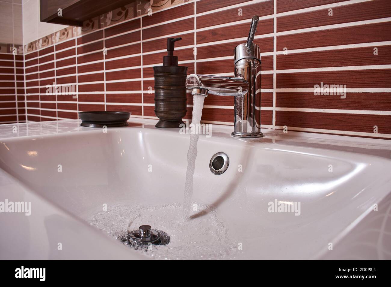 Chrome shiny faucet in an open bathroom with running water Stock Photo