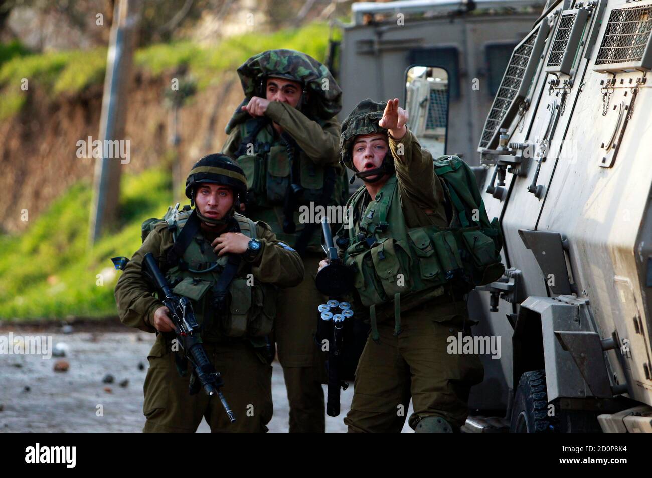 An Israeli soldier points during clashes with stone throwing Palestinians protesting against a nearby Jewish settlement in the West Bank village of Burin, south of Nablus February 2, 2013. Israeli soldiers used tear gas and stun grenades on Saturday to disperse about 150 Palestinians trying to block expansion of Israeli settlements in the occupied West Bank. Both sides sustained light injuries as the soldiers removed about a dozen tents and small huts from land adjacent to the Palestinian northern West Bank village of Burin, Palestinian witnesses and the Army said. REUTERS/Ammar Awad (WEST BAN Stock Photo