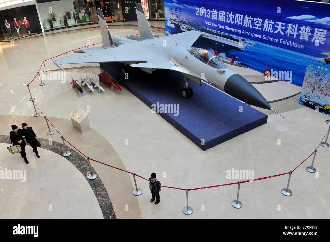 People walk past a model of J-15 fighter aircraft during an aerospace  science exhibition inside a shopping mall in Shenyang, February 26, 2013.  The exhibition runs from February 6 to February 28.