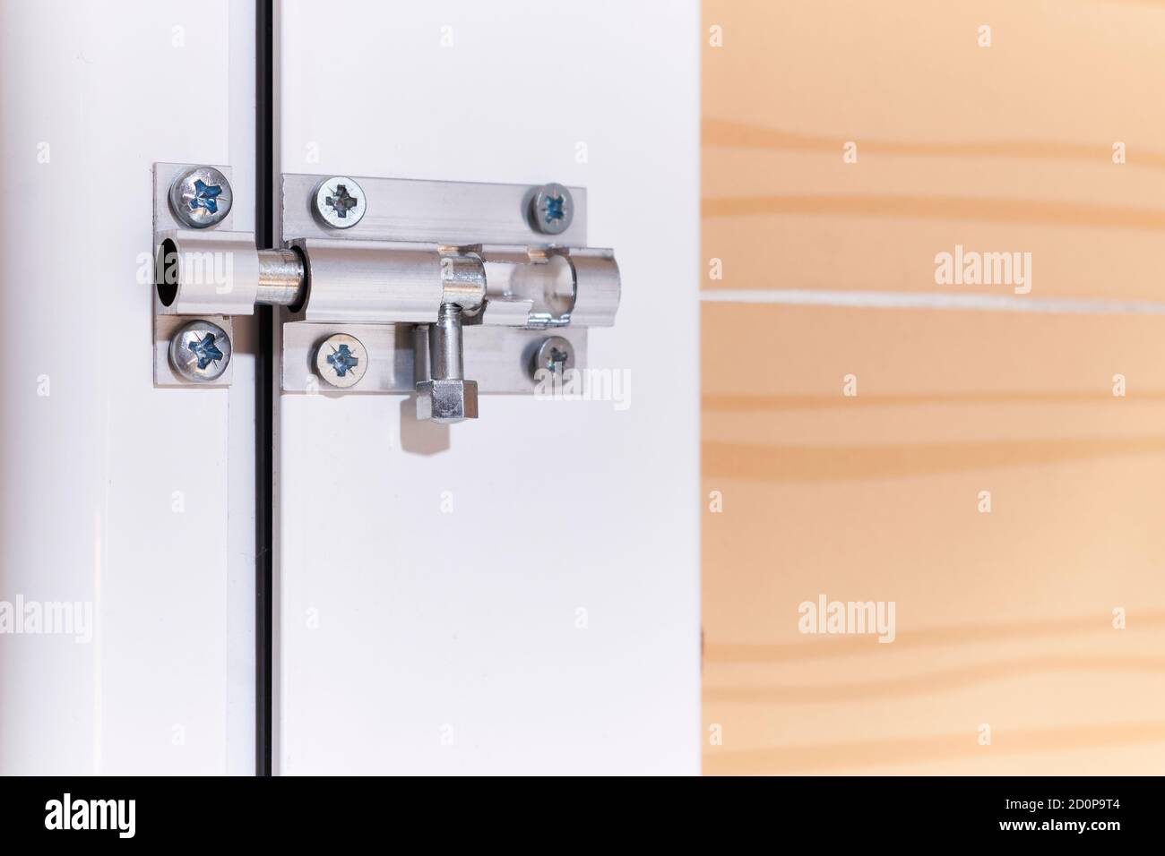 Aluminum manual latch bolt installed on a white lacquered aluminum carpentry door inside a home Stock Photo