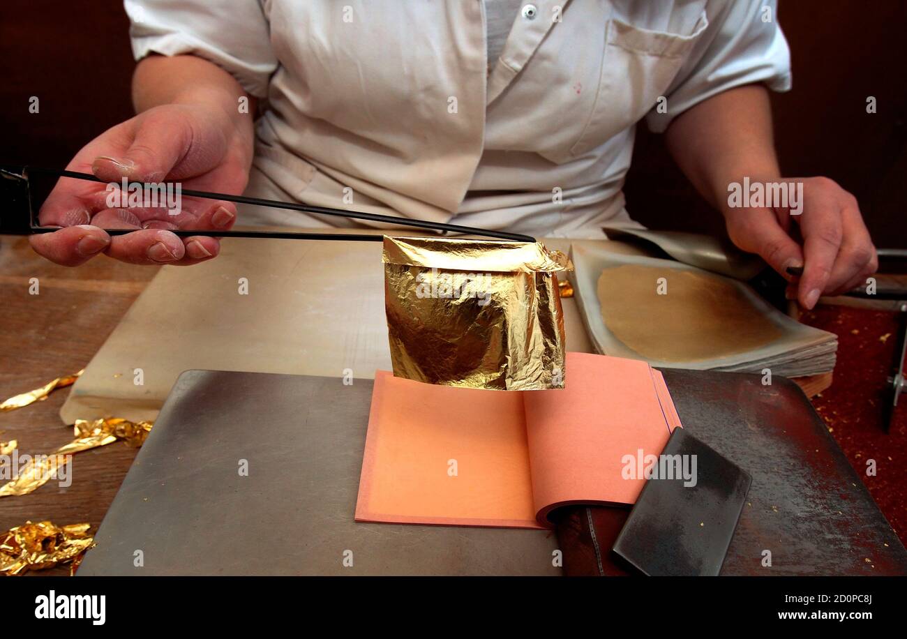 A worker places sheets of finished gold leaf between tissue paper at Erich  Dungl's gold leaf workshop in Schwechat March 4, 2014. Each handmade sheet  of gold leaf is produced by squeezing