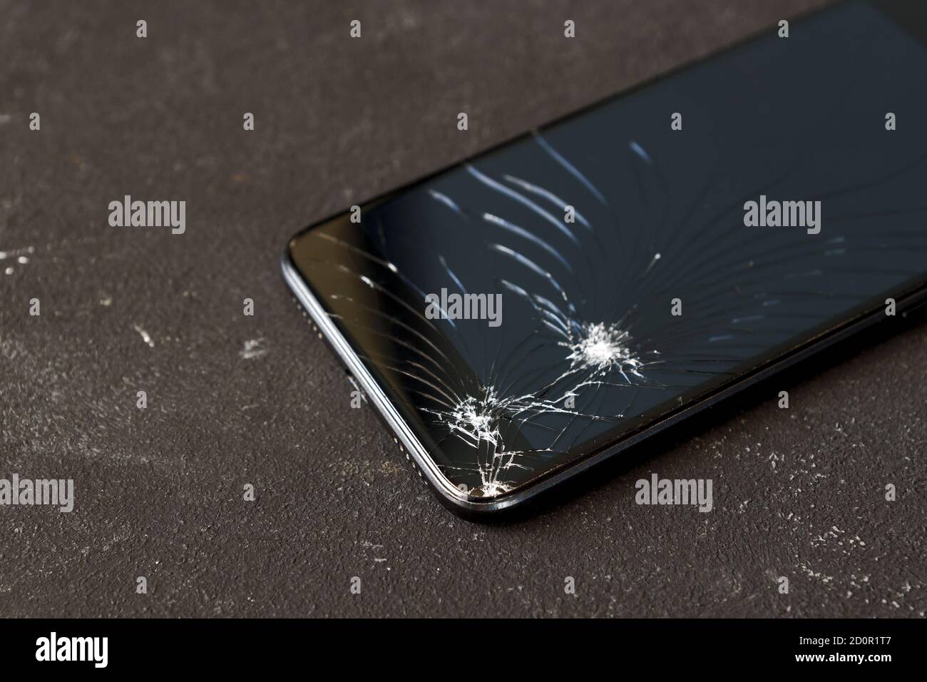 Broken glass of black smart phone on the dark background. Selective focus. Stock Photo