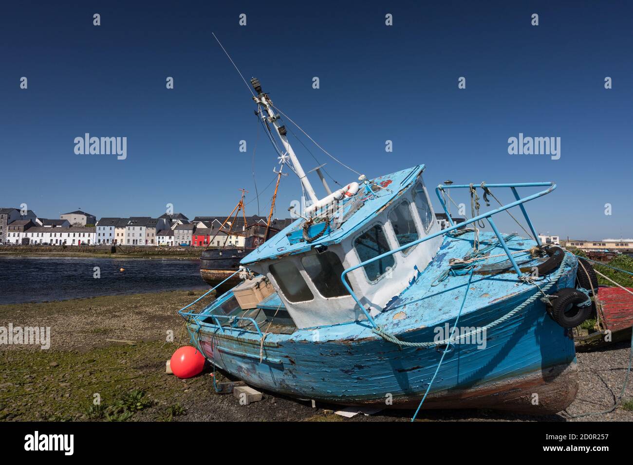 Old colourful blue fishing boat and houses in the distance of the