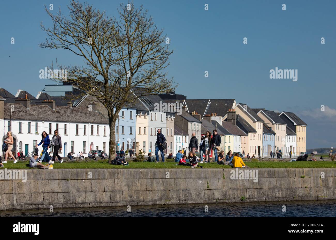 GALWAY CITY, IRELAND - 5th May, 2018: People enjoying a sunny spring day along the bank of Corrib river in the Claddagh area of Galway city, Ireland Stock Photo