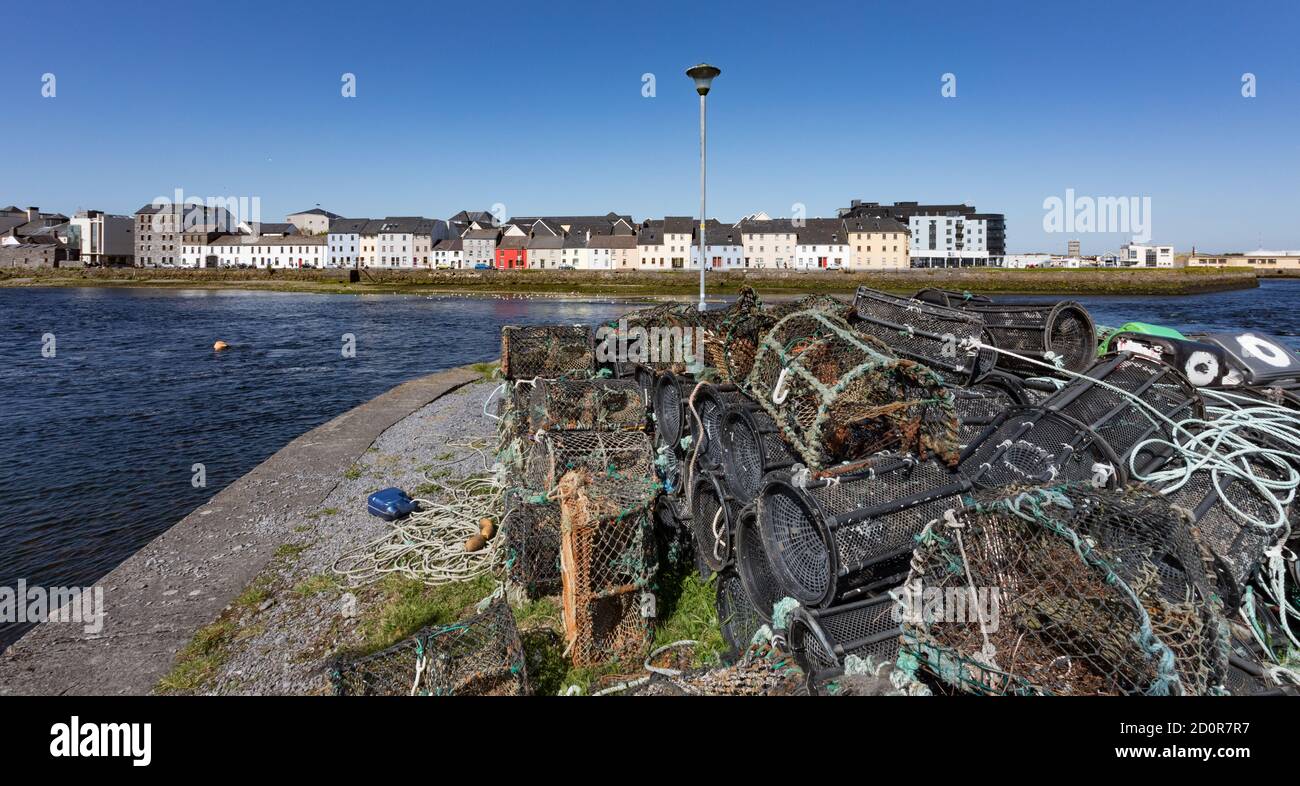 Empty Fishing crab pots piled up on harbour dock overlooking houses in