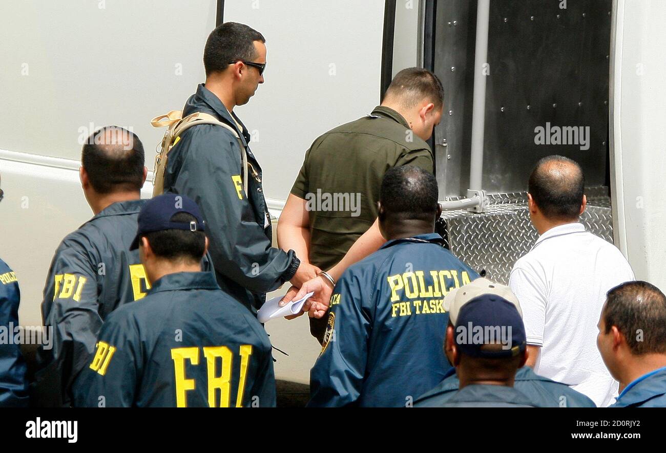 An FBI agent escorts one of the police officers and prison guards arrested in a major anti-corruption operation across the U.S. Caribbean territory following his first court appearance at the Puerto Rico Federal Court Building in San Juan, October 6, 2010. REUTERS/Ana Martinez (PUERTO RICO - Tags: POLITICS CRIME LAW) Stock Photo