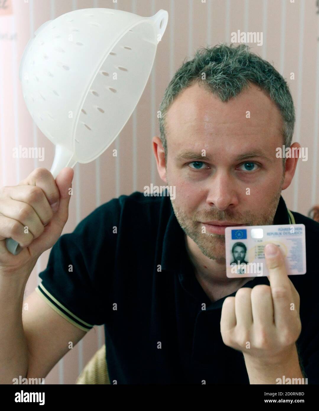 Austrian businessman Niko Alm poses with his Austrian driver's licence,  depicting him wearing a pasta strainer, during a news conference in Vienna,  July 14, 2011. Alm is promoting the Church of the