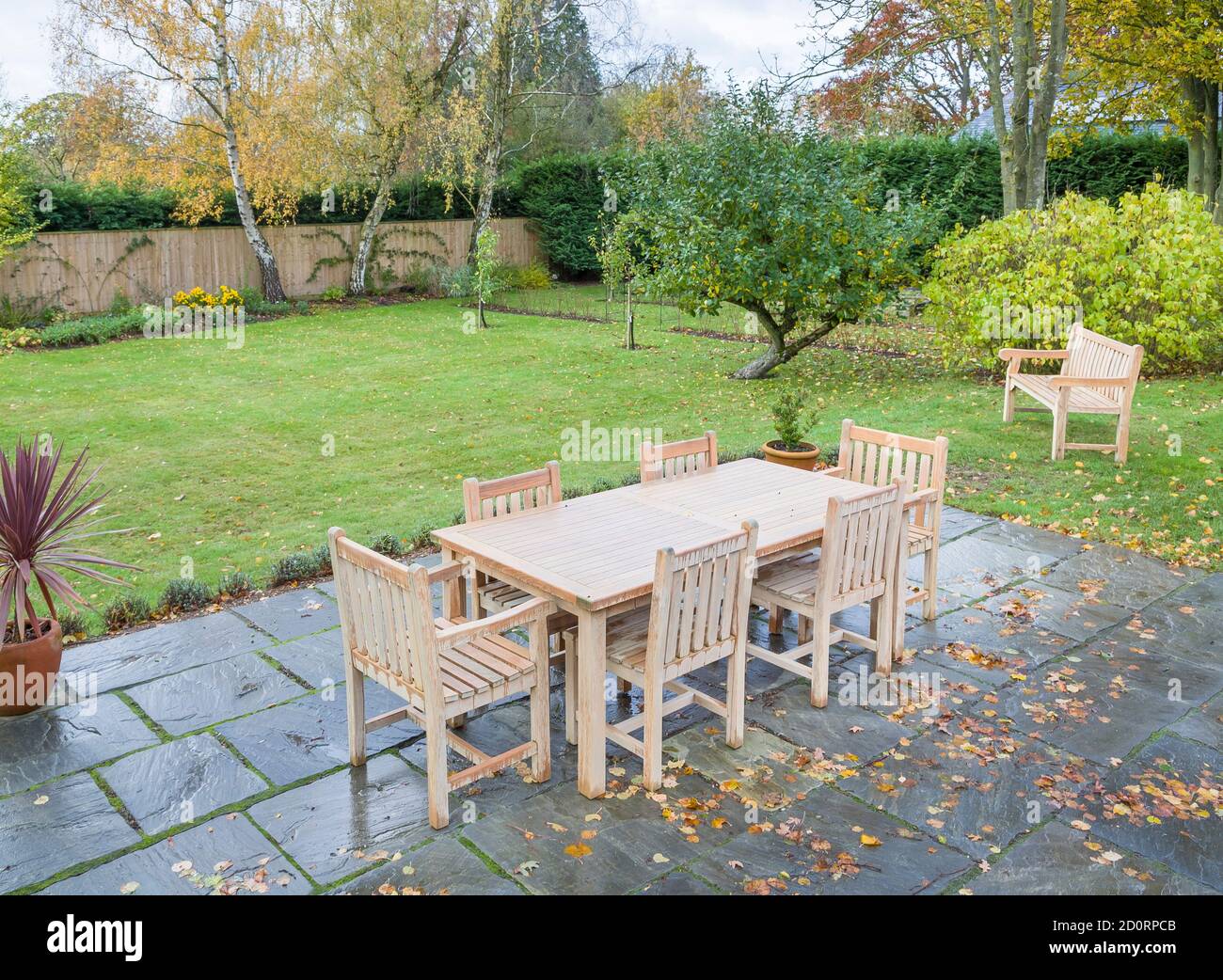 Large UK back garden in autumn with wooden furniture on a garden patio terrace Stock Photo