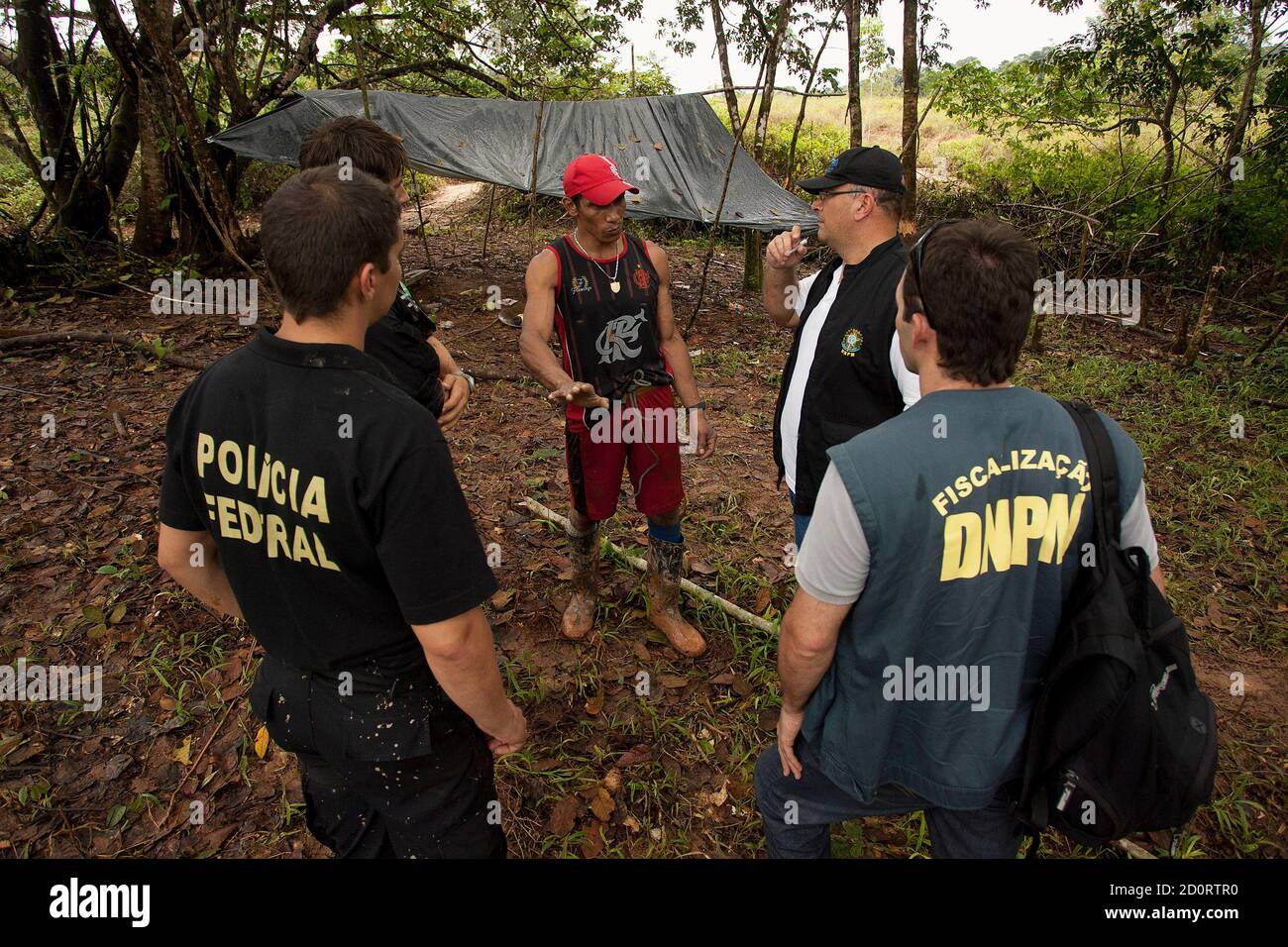 A wildcat miner is questioned by Brazilian Army soldiers and Federal Police officers about his activities, during a patrol for drug smugglers and illegal gold mines along the Cassipore River near the border with French Guiana, in this picture taken May 9, 2012. Brazil's Army began Operation Agate with the Federal Police, Customs, the National Aviation Agency, and the government's environmental police force (IBAMA), along a large part of the northern border to combat smuggling and environmental crimes, according to an Army communique. Picture taken May 9, 2012. REUTERS/Paulo Santos (BRAZIL - Ta Stock Photo