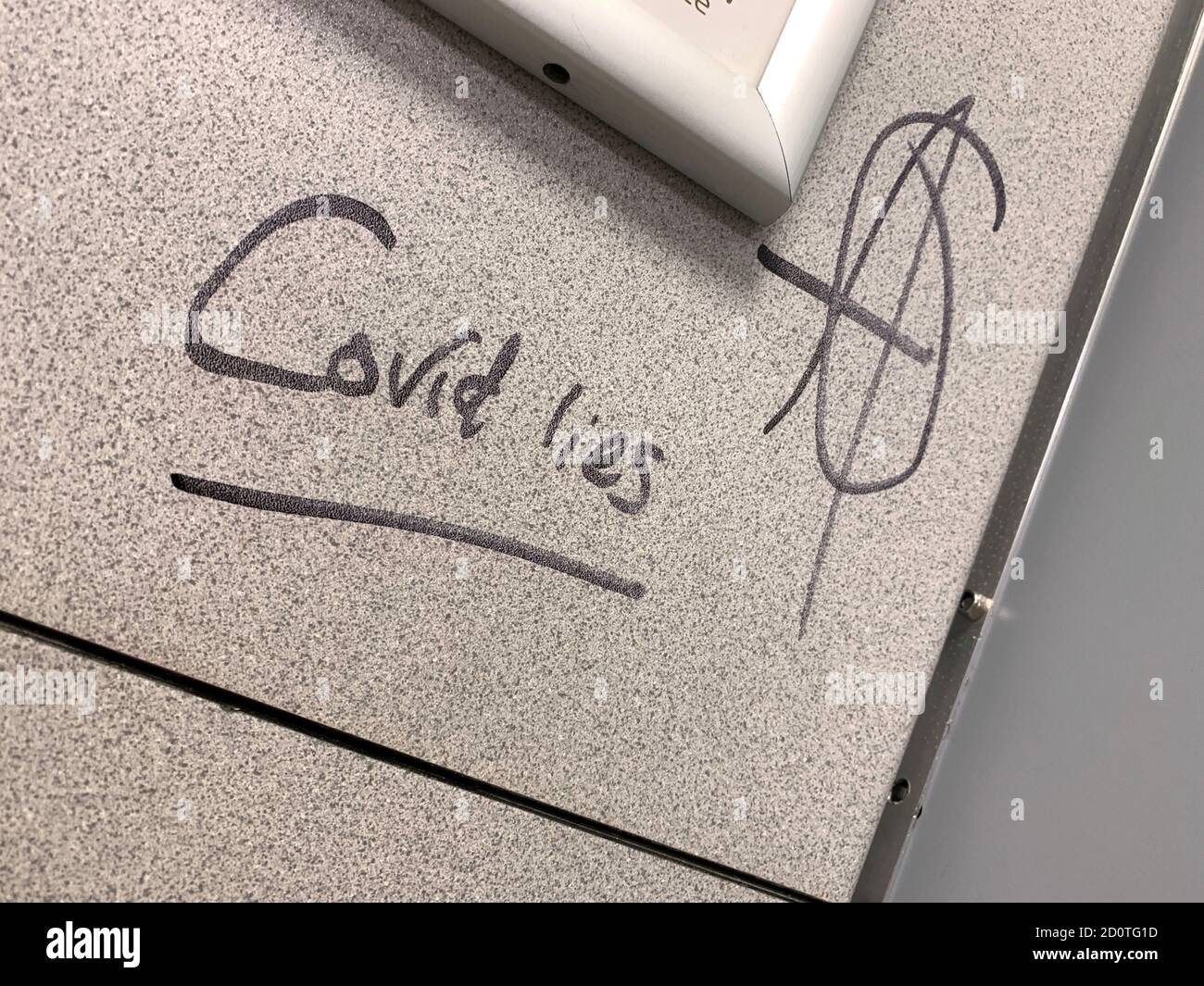 Graffiti that reads 'Covid lies' next to the anarchy logo is seen in a public toilet at the M3 motorway Moto Services near Winchester, Britain, October 3, 2020.    REUTERS/Russell Boyce Stock Photo
