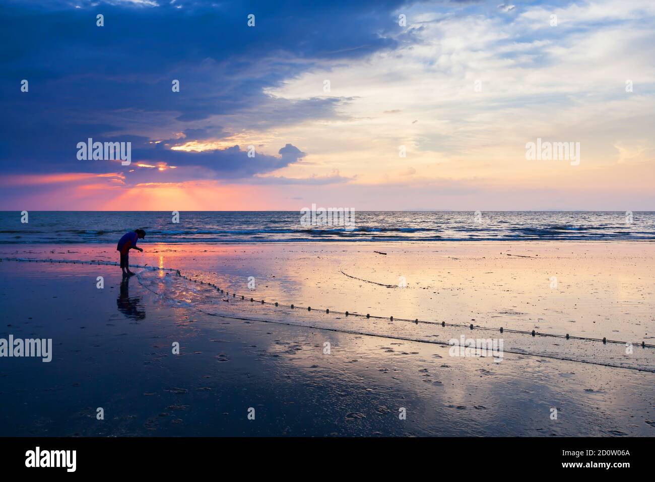 An Asian woman catching saltwater fish by using the fishing net on the  beach at dusk, dramatic sunset sky in the backgrounds. South Thailand Stock  Photo - Alamy