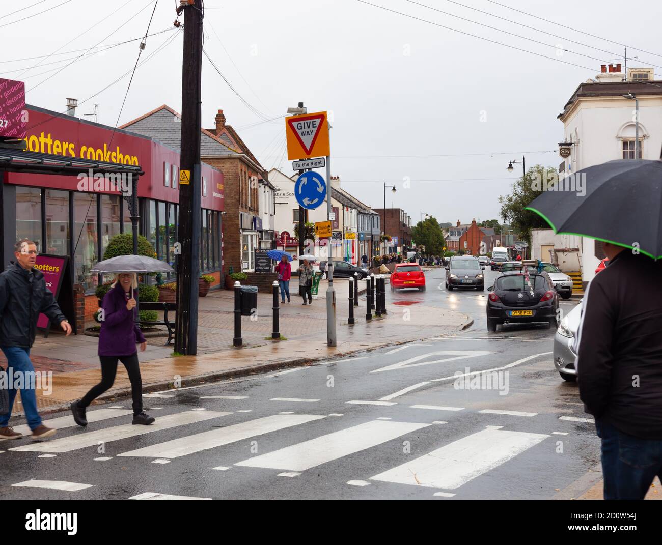 Street view of high street shoppers crossing the road on a rainy day