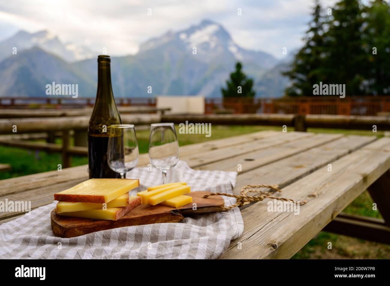 Cheese collection, French comte, beaufort or abondance cow milk cheese served outdoor with Alps mountains peaks in summer on background Stock Photo