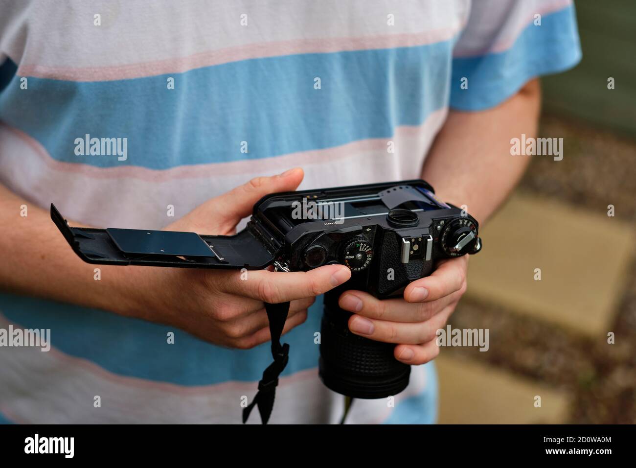 A young man loads photographic film into an analogue camera, a medium seeing a resurgence in recent years (MR) Stock Photo