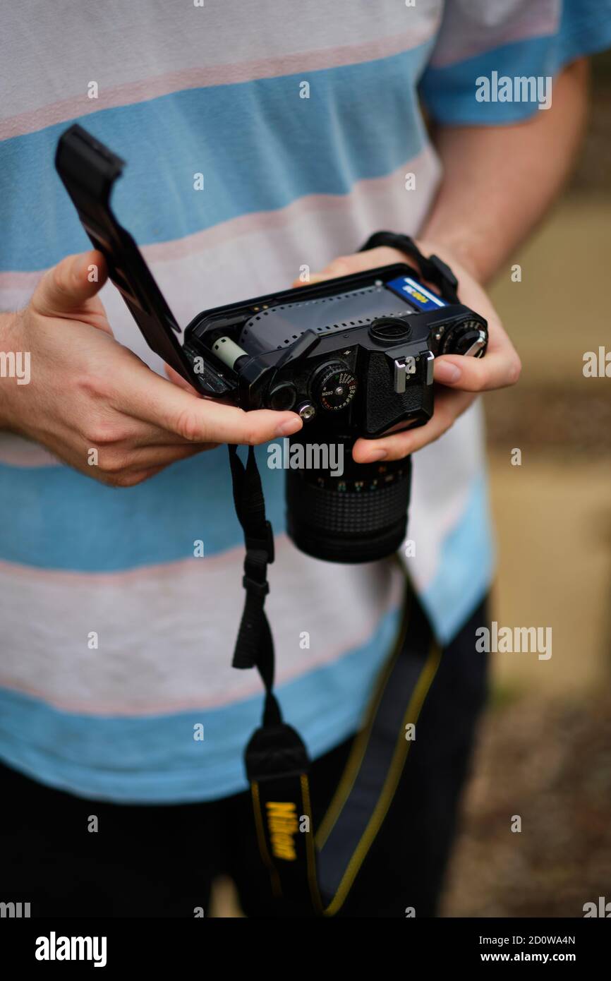 A young man loads photographic film into an analogue camera, a medium seeing a resurgence in recent years (MR) Stock Photo