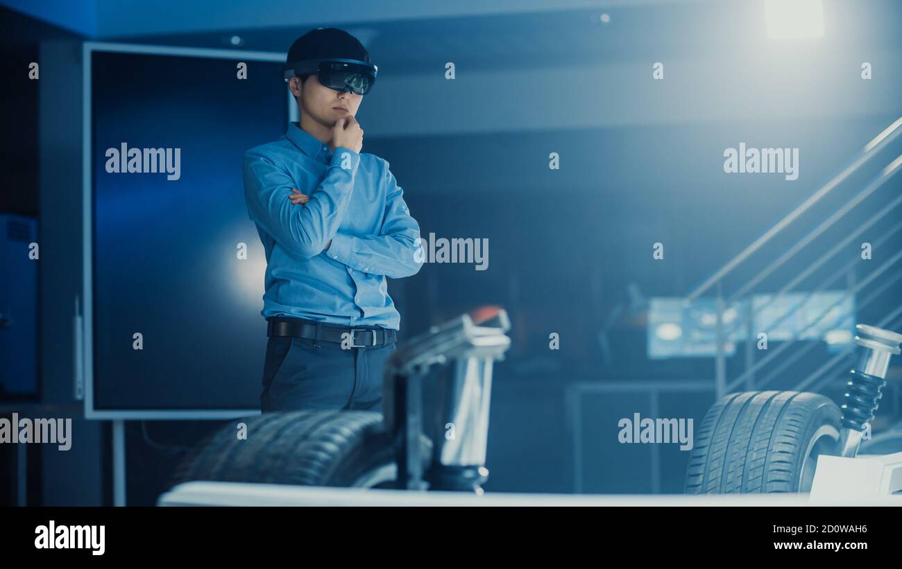 Automotive Engineer Working on Electric Car Chassis Platform, Using Augmented Reality Headset. In Innovation Laboratory Facility Concept Vehicle Frame Stock Photo