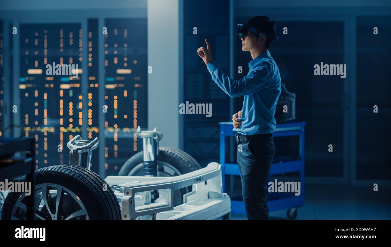 Automotive Engineer Working on Electric Car Chassis Platform, Using Augmented Reality Headset with Touching Gestures. In Innovation Laboratory Stock Photo