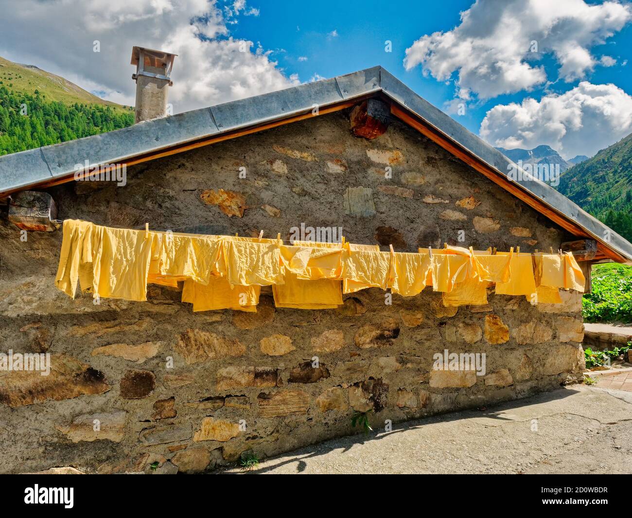 Stone mountain refuge with yellow clothes hanging outside to dry Alps, Trentino, Italy, Europe Stock Photo