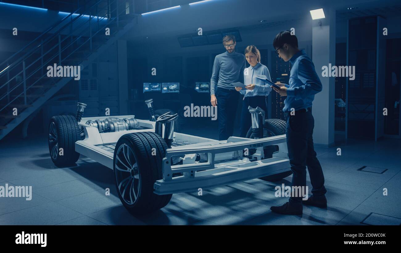 Diverse Automobile Engineers Talking while Working on Electric Car Platform Chassis Prototype. In Automotive Innovation Facility Concept Vehicle Frame Stock Photo