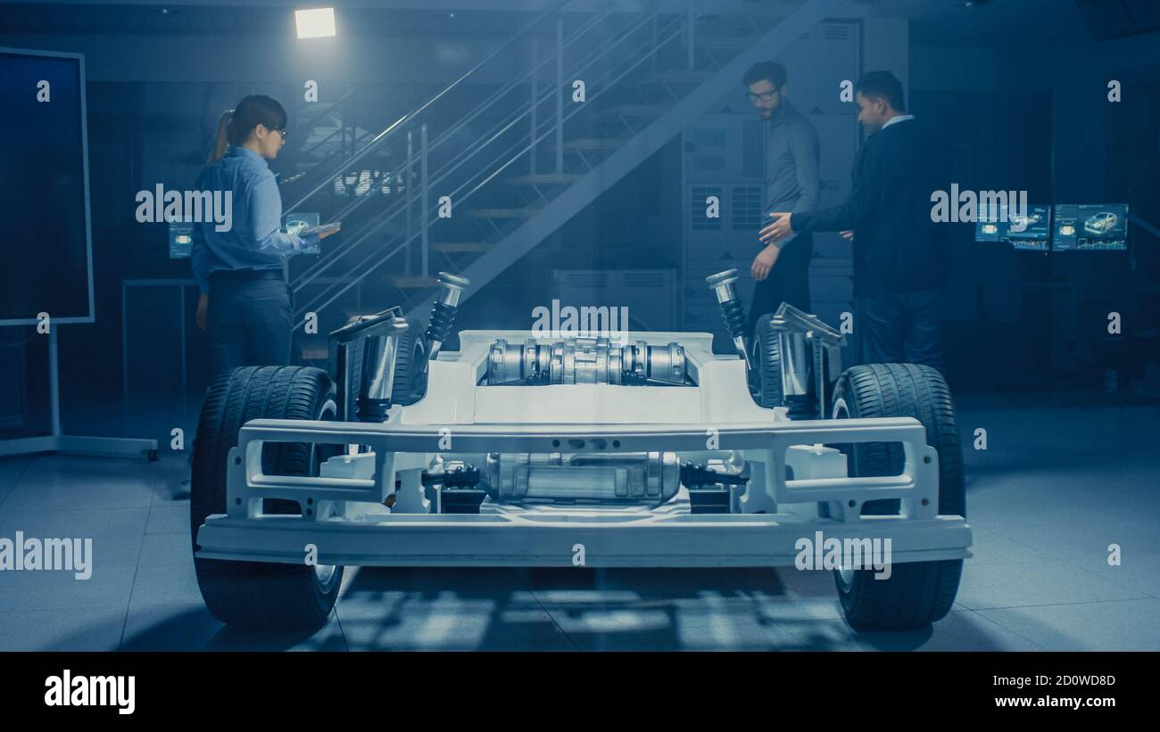 Team of Automobile Design Engineers in Automotive Innovation Facility Working on Electric Car Platform Chassis Prototype that Includes Wheels Stock Photo