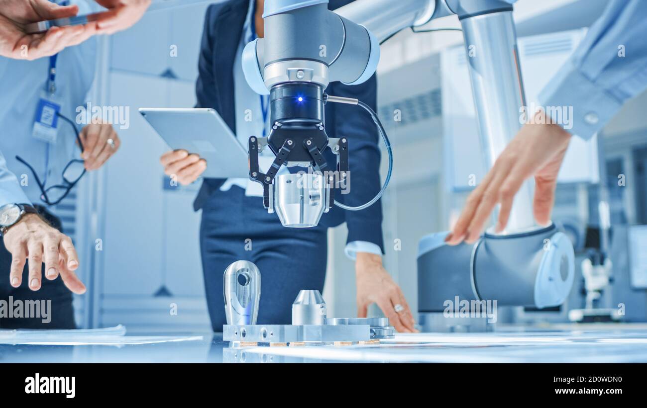 Team of Industrial Robotics Engineers Gathered Around Table With Robot