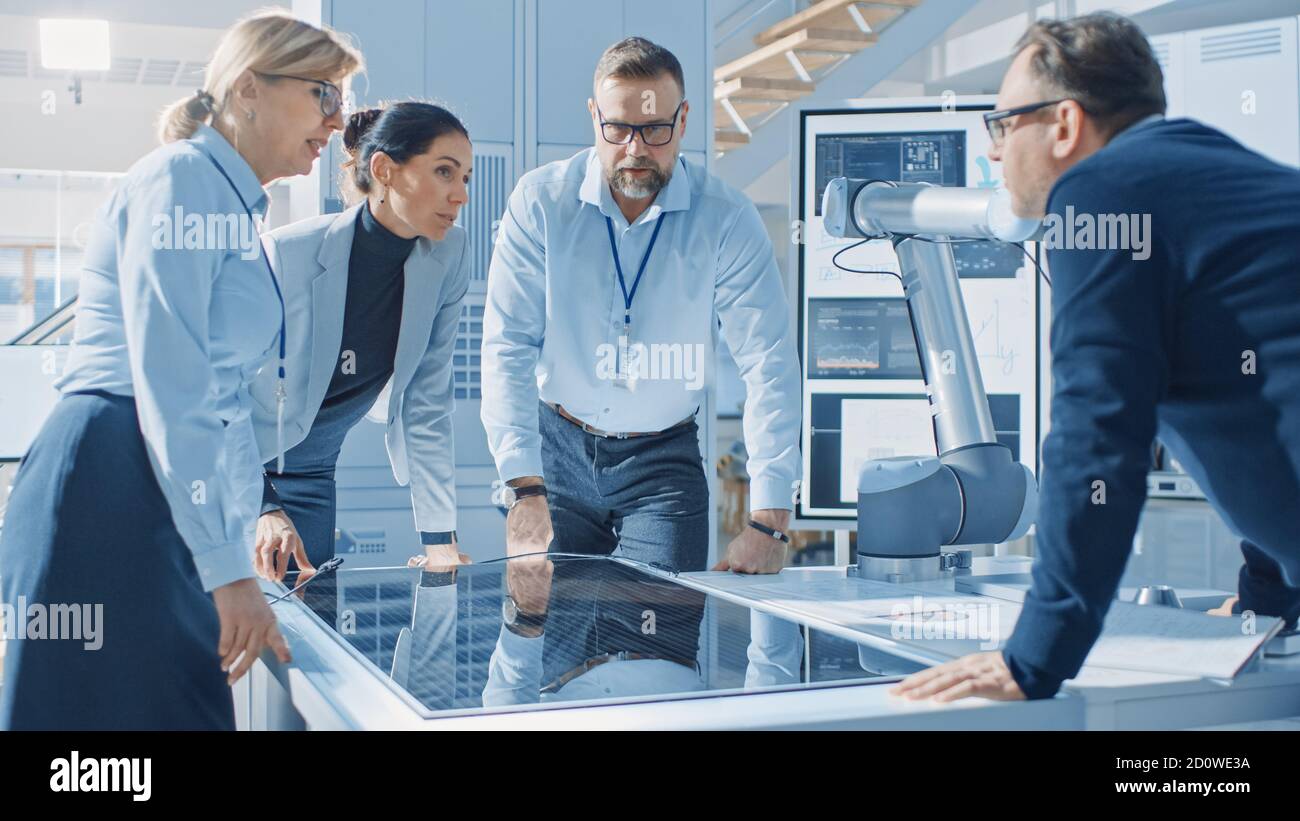 Team Meeting of Renewable Energy Engineers Working on an Innovative More Efficient Solar Panel Battery Concept. Group of Specialists Gathered Around Stock Photo