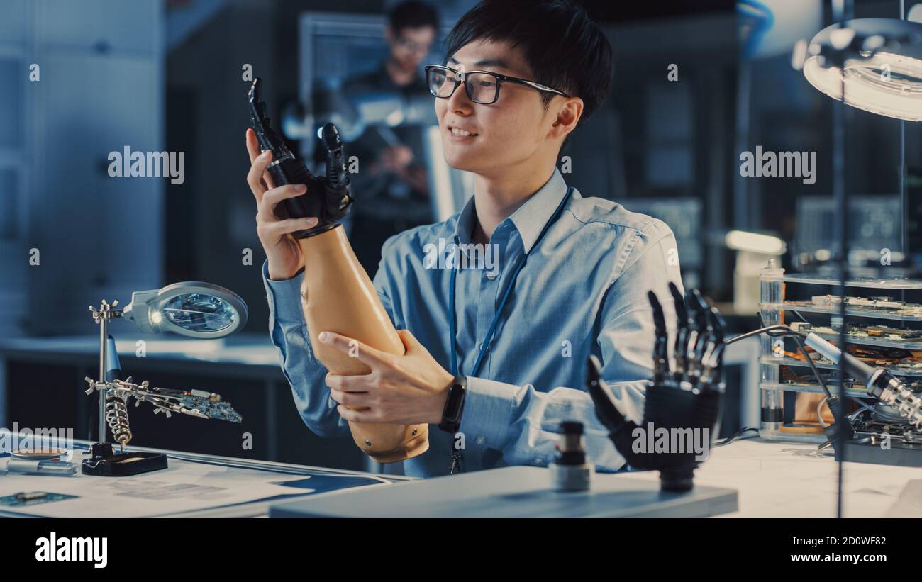 Futuristic Prosthetic Robot Arm Being Tested by a Professional Japanese Development Engineer in a High Tech Research Laboratory with Modern Computer Stock Photo