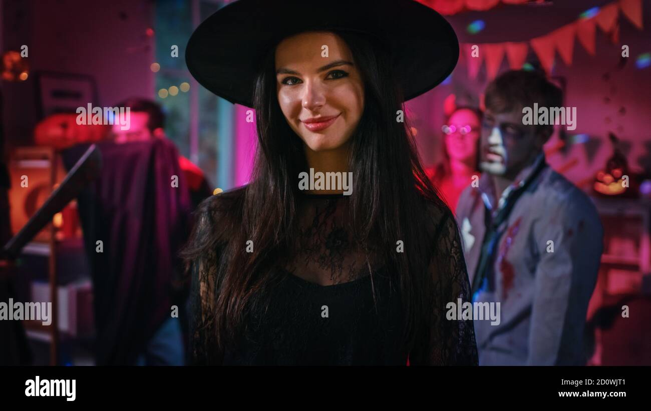 Halloween Costume Party: Gorgeous Young Witch Wearing Dress and Hat Poses seductively. Background: Beautiful She Devil, Scary Death, Count Dracula Stock Photo