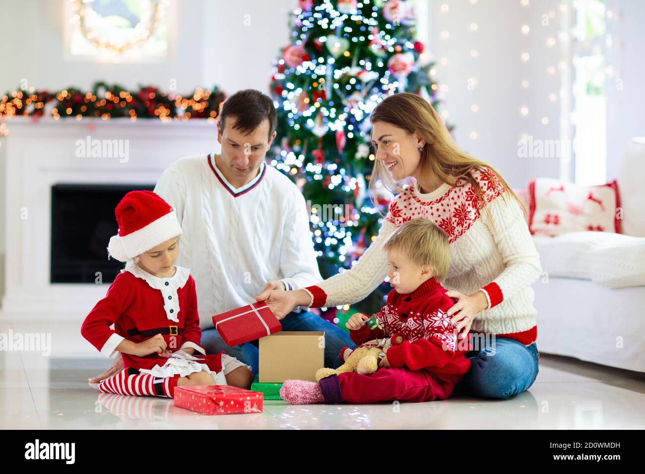 Family celebrating Christmas. Parents and kids decorate Xmas tree and open  gifts. Child with present box. Kid opening presents. Home decoration for w  Stock Photo - Alamy