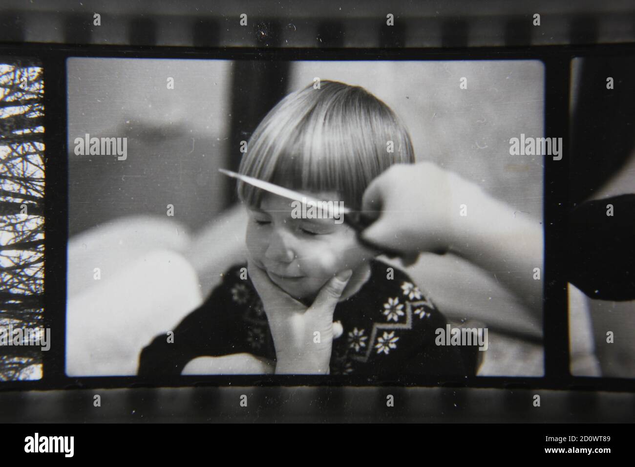 Fine 1970s vintage black and white photography of a young girl getting a pageboy haircut by her mother. Stock Photo