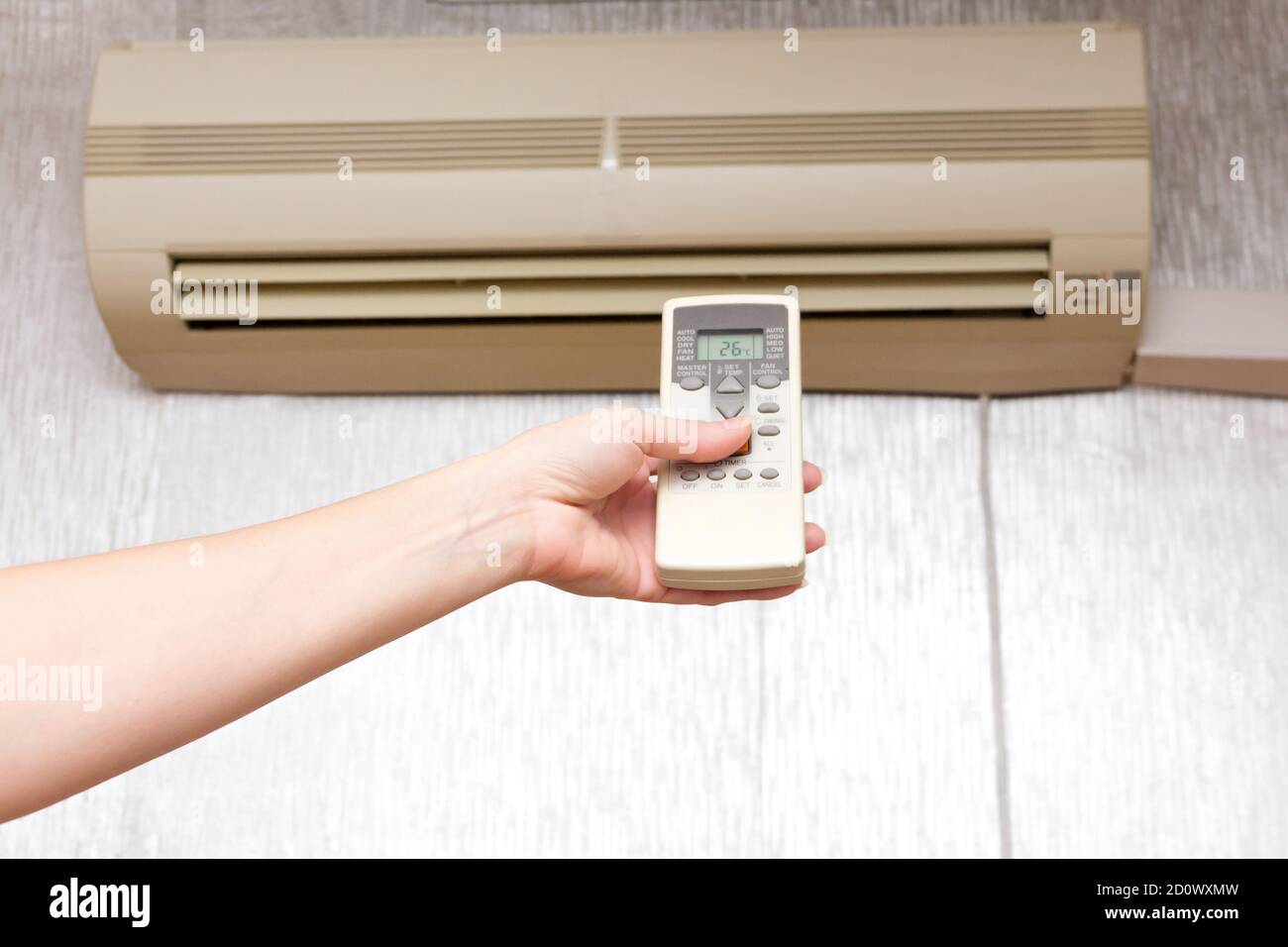 The woman turns on the household split system using the remote control. Stock Photo