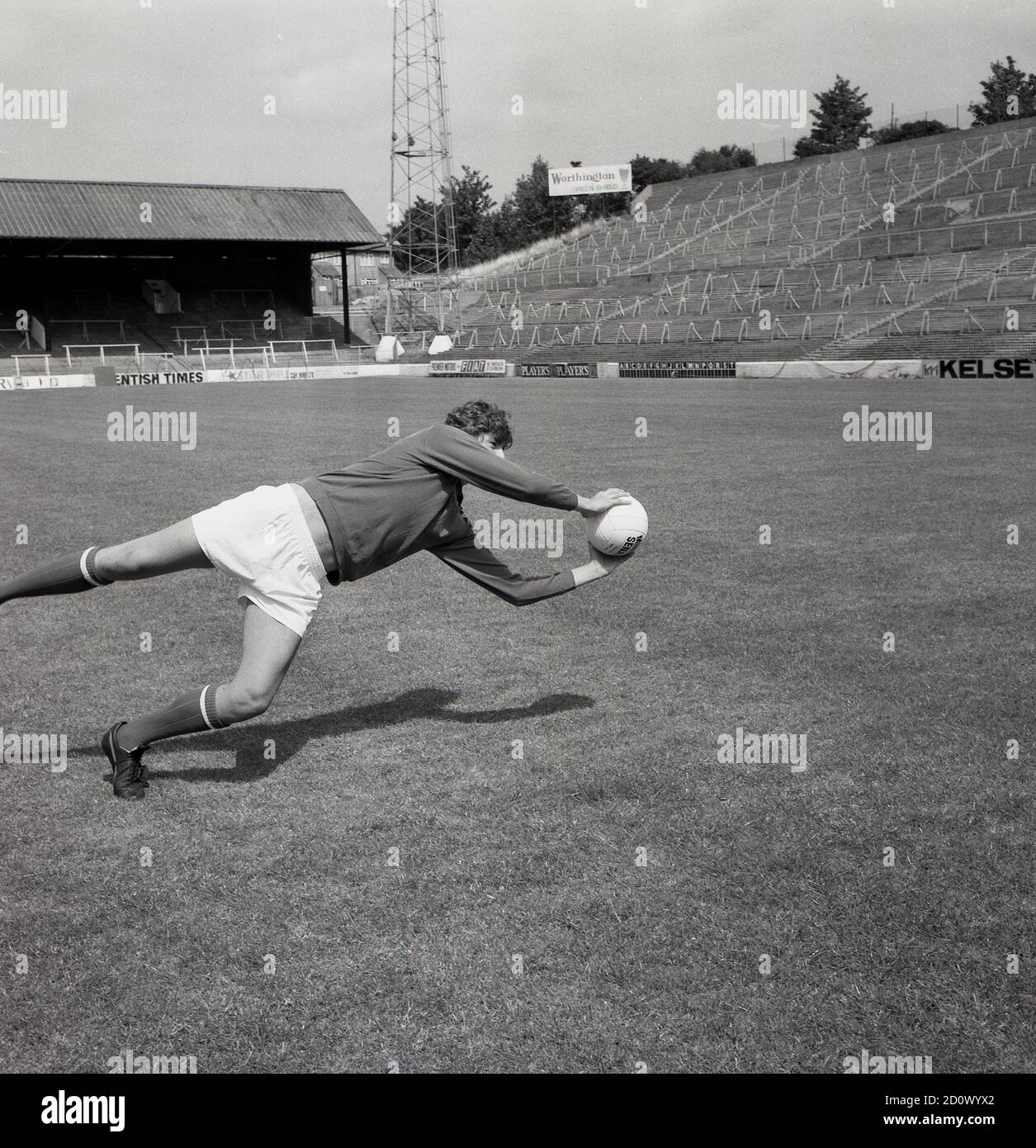 1960s, historical, goalkeeper with ball in hands, Charlton Athletic Footall Club, pre-season training, Southeast London, England, UK. In this era, football was played at grounds with traditional terraces as can be seen here. At the Valley as it was known, the banking the terraces was large and quite steep. Stock Photo
