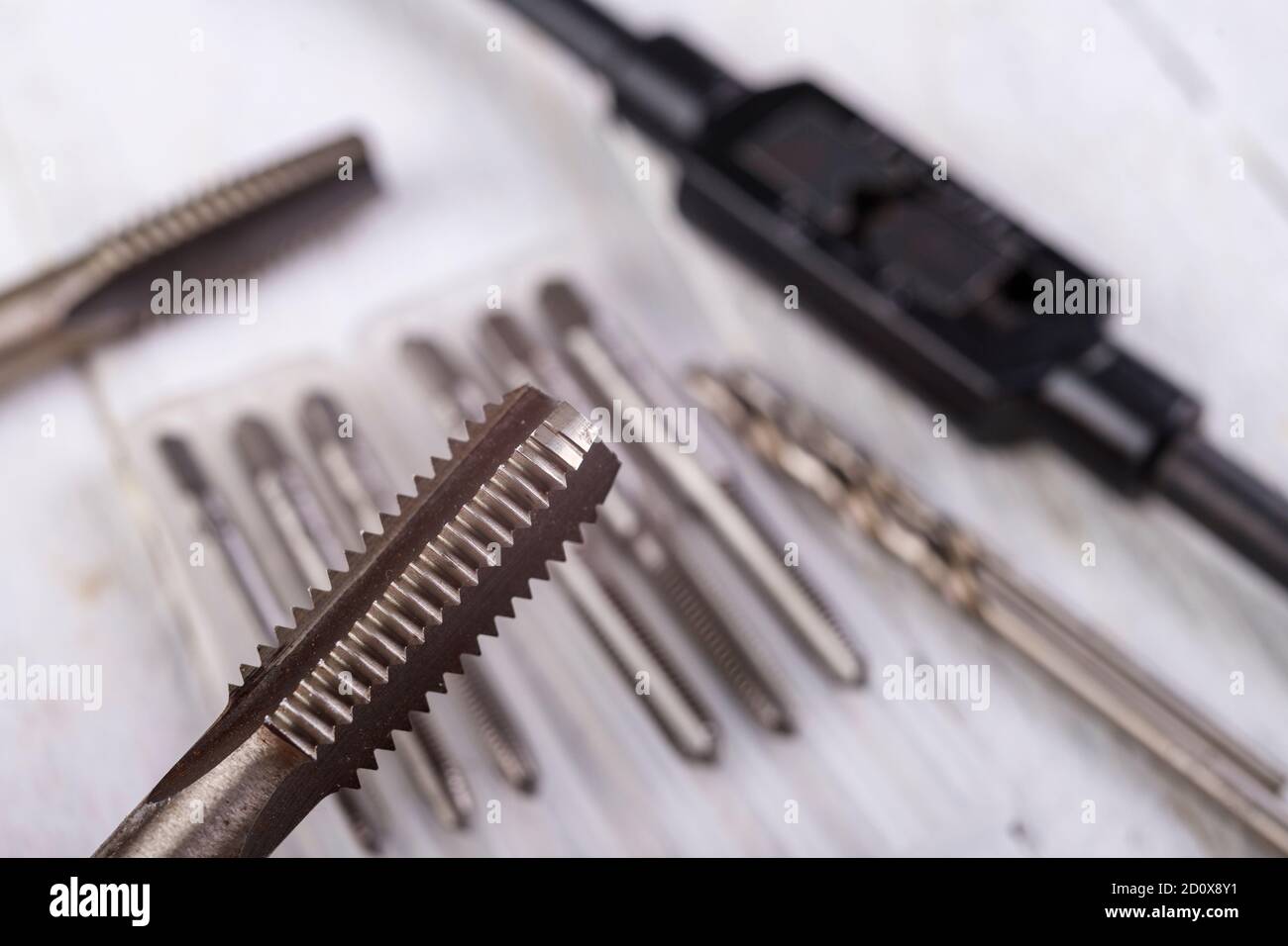Metal taps prepared for work. Accessories in the locksmith's workshop. Light background. Stock Photo