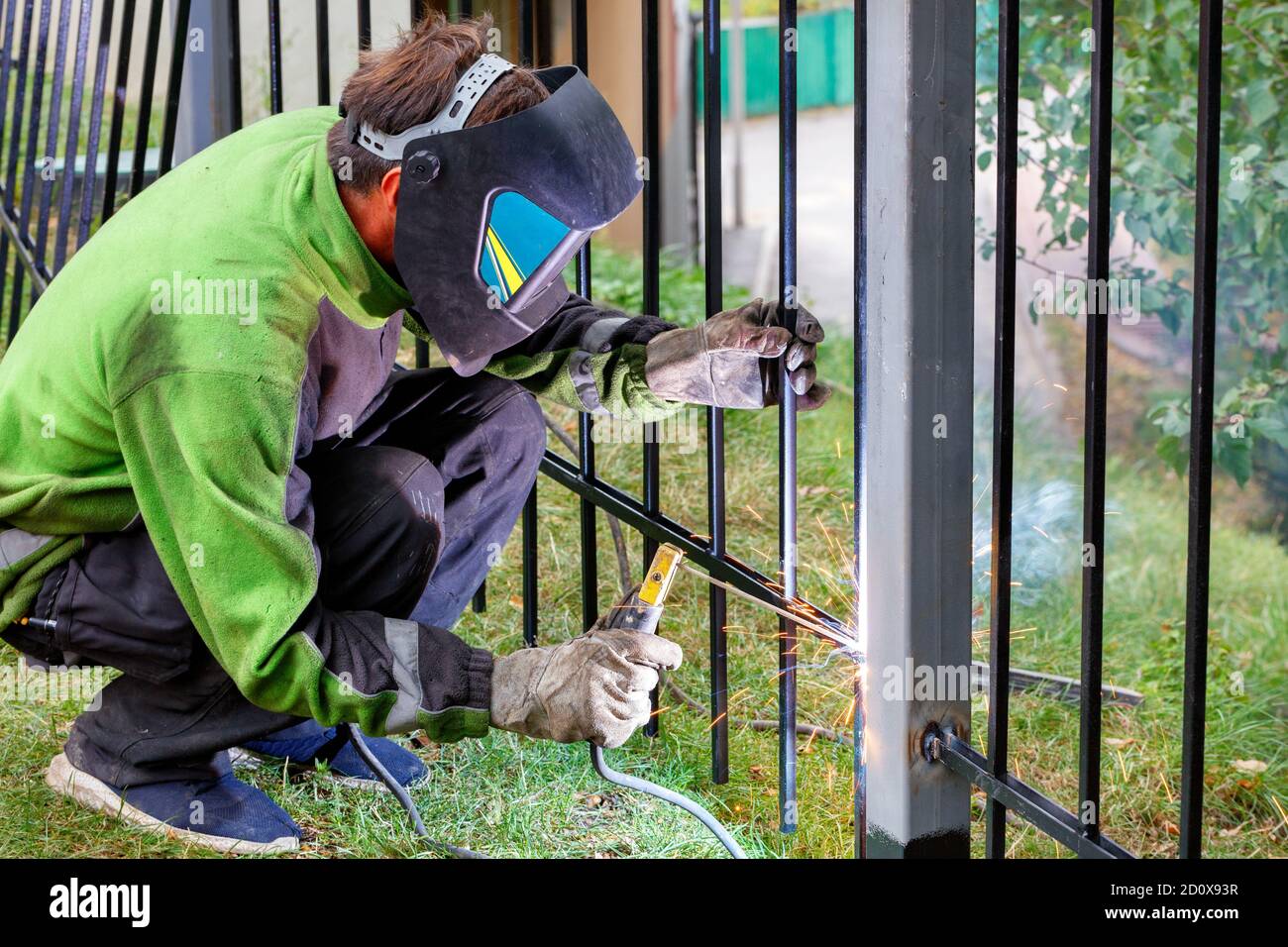 A welder wearing protective clothing, helmet and gloves welds a metal