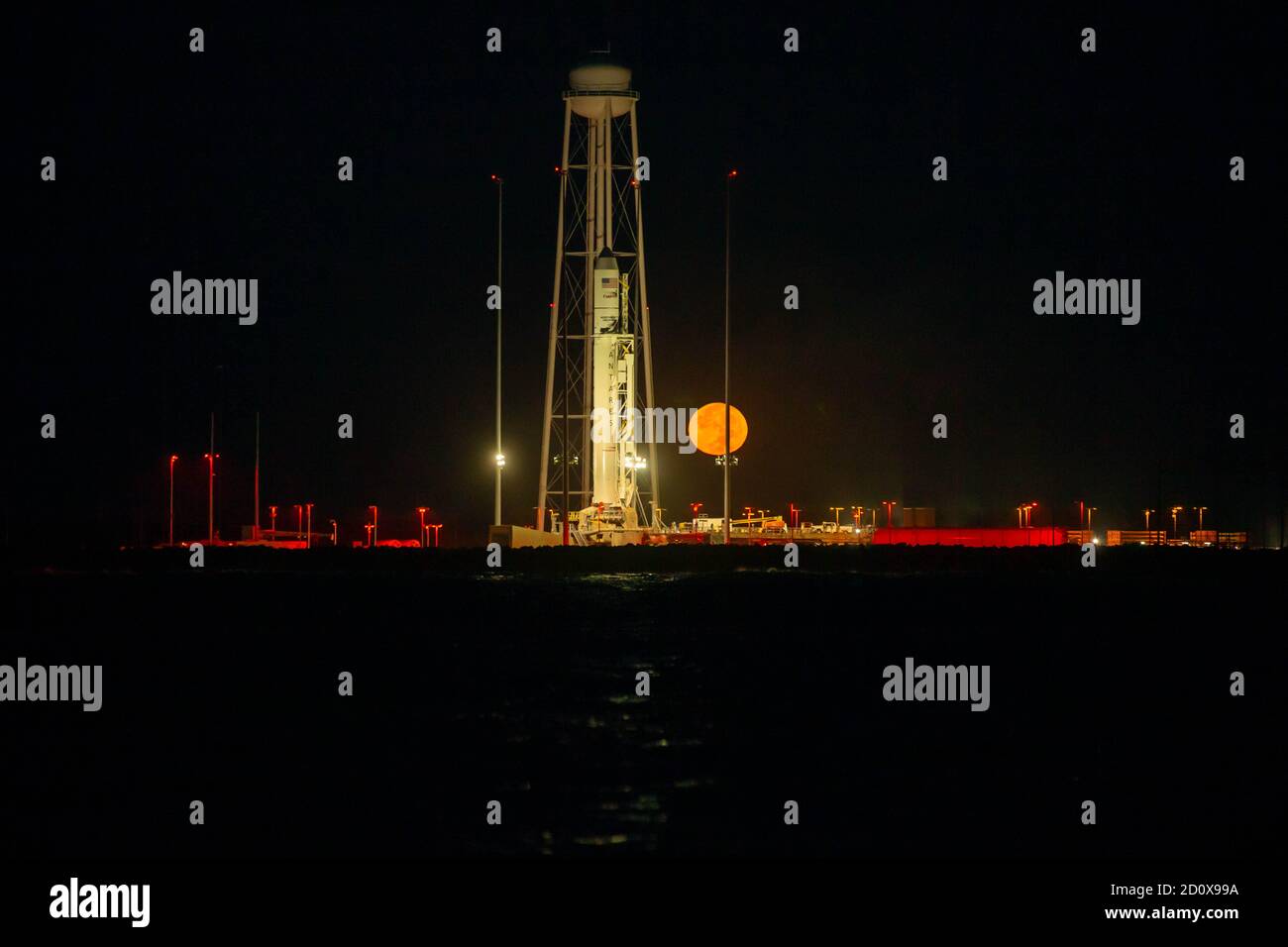 The Northrop Grumman Antares rocket, with Cygnus resupply spacecraft onboard, is ready for launch as the harvest moon rises behind at the Mid-Atlantic Regional Spaceport in the NASA Wallops Flight Facility October 1, 2020 in Wallops, Virginia. The commercial cargo resupply mission is carrying 8,000 pounds of supplies and equipment to the International Space Station. Stock Photo