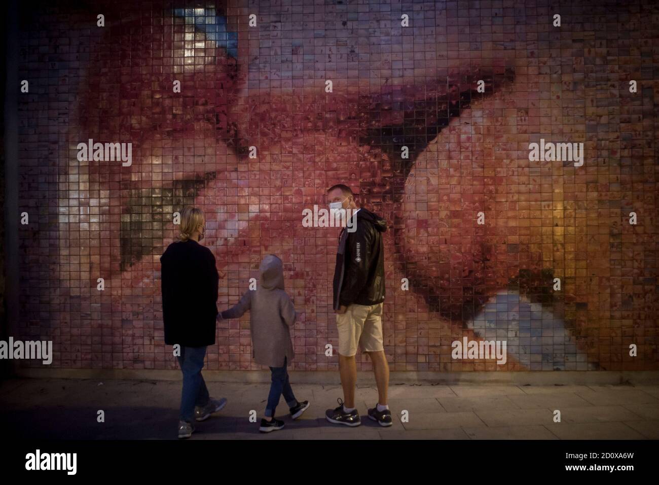 Barcelona, Spain. October 3, 2020, Barcelona, Catalonia, Spain: In Barcelona a family wearing face masks to prevent the spread of coronavirus looks at a work of street art made of small photos that together form a kiss. Signs of a second wave of Covid-19 infections breaking over Spain have made to impose new partial lockdown on its capital Madrid. Credit:Jordi Boixareu/Alamy Live News Stock Photo