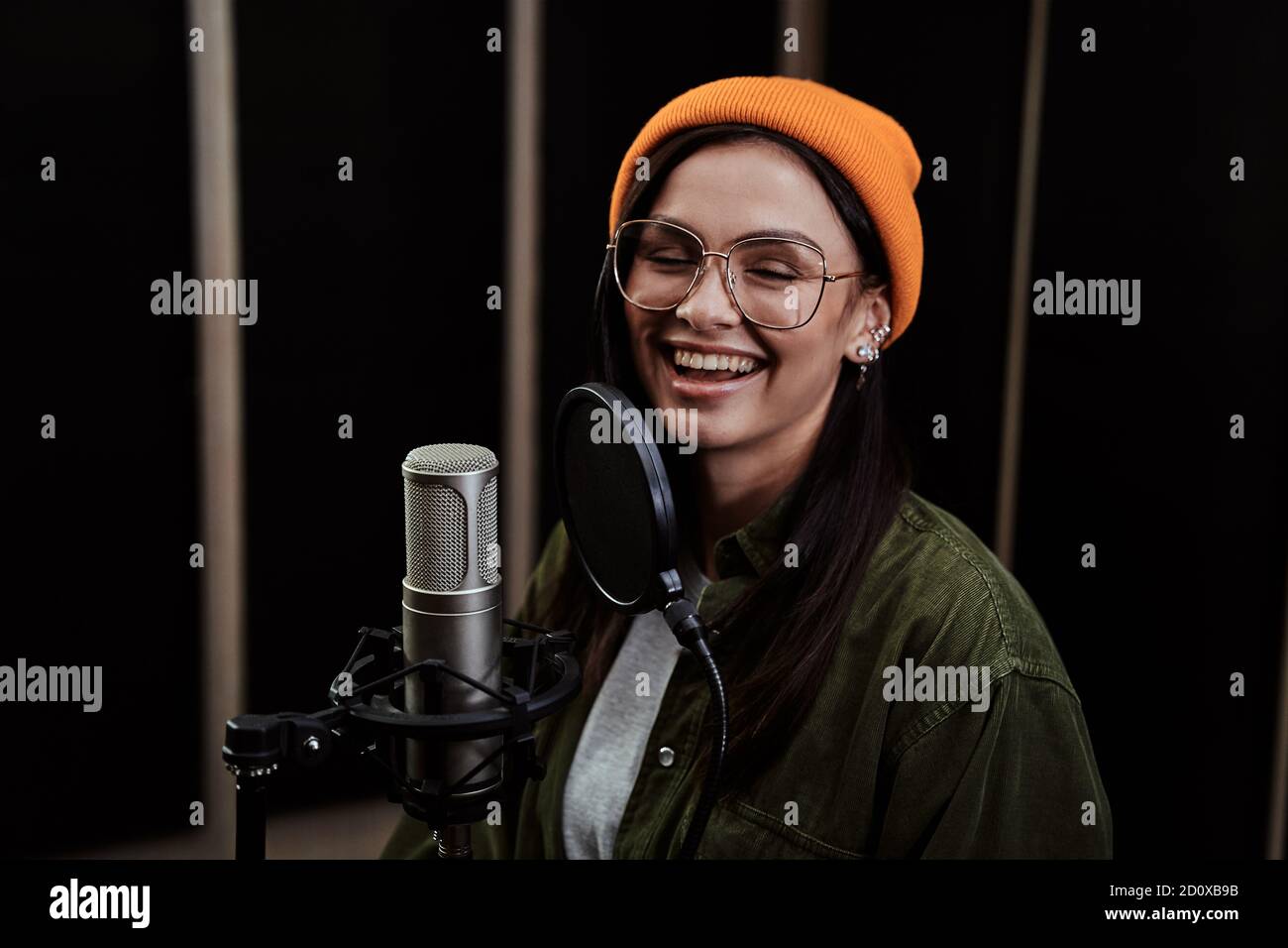 Portrait of cheerful young woman, hip hop artist singing into a ...