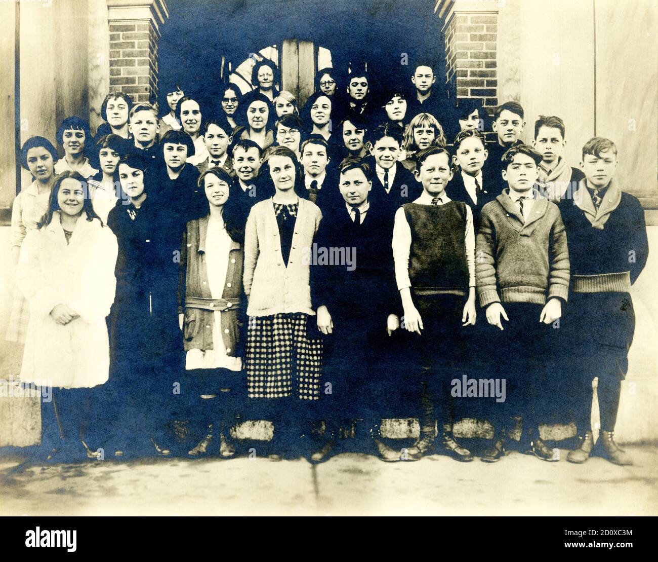 This photo dates to around 1922 and shows a class at Jireh Swift School in the North End of New Bedford, Massachusetts,at the end of the school year and graduating to the next class.  This elementary school was built in 1909 and named after Jireh Swift, a prominent merchant.  He was the founder of Swift & Allen, an organization that served the whaling industry as agents, ship chandlers, and commission merchants. Swift & Allen were major suppliers of cordage, iron ware, groceries, and other goods needed to outfit whaling vessels of New Bedford and nearby ports. Stock Photo