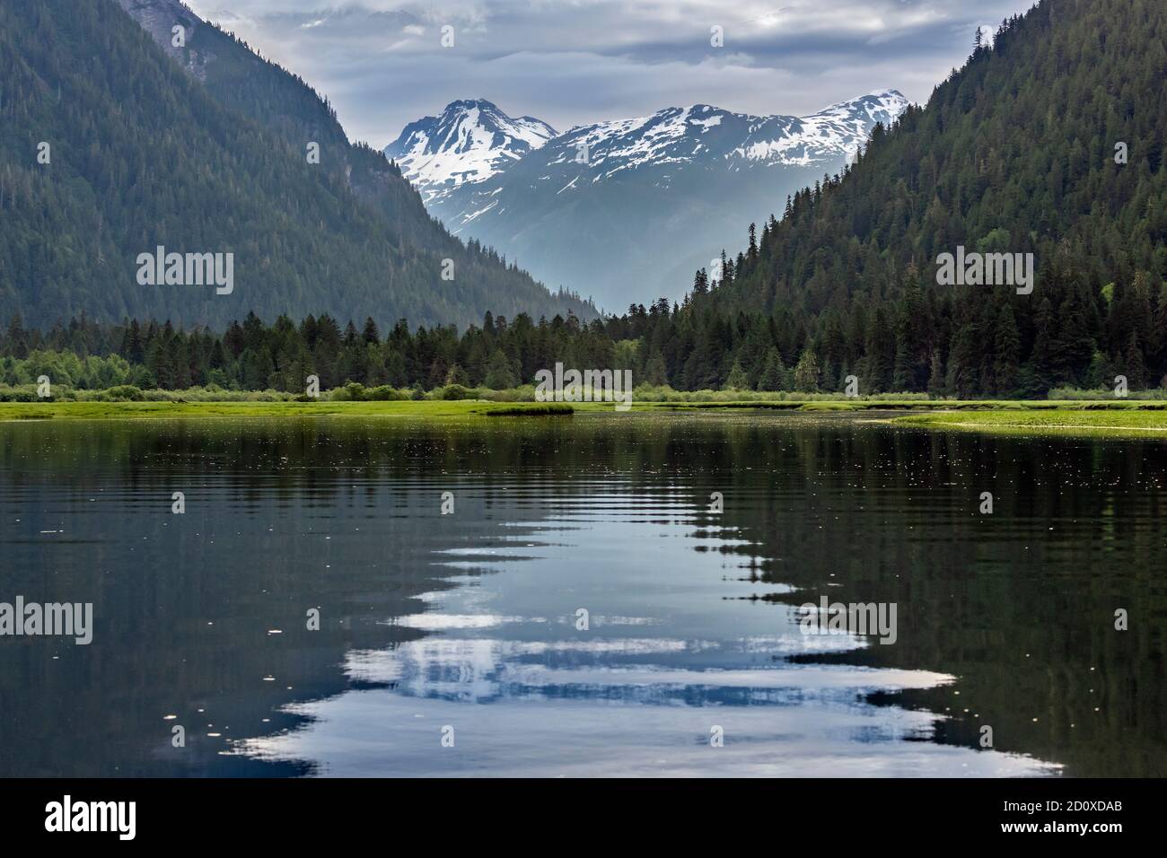 Snow-covered mountain, ripples and reflections, Khutzeymateen estuary, BC Stock Photo